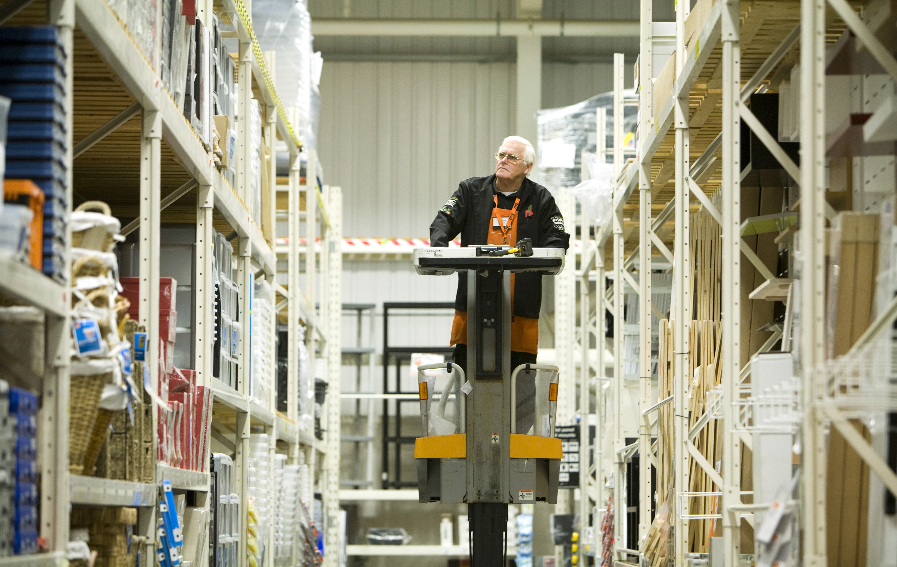 Pensioner Ken Slater, a B&Q employee, using a lift to check stock levels.