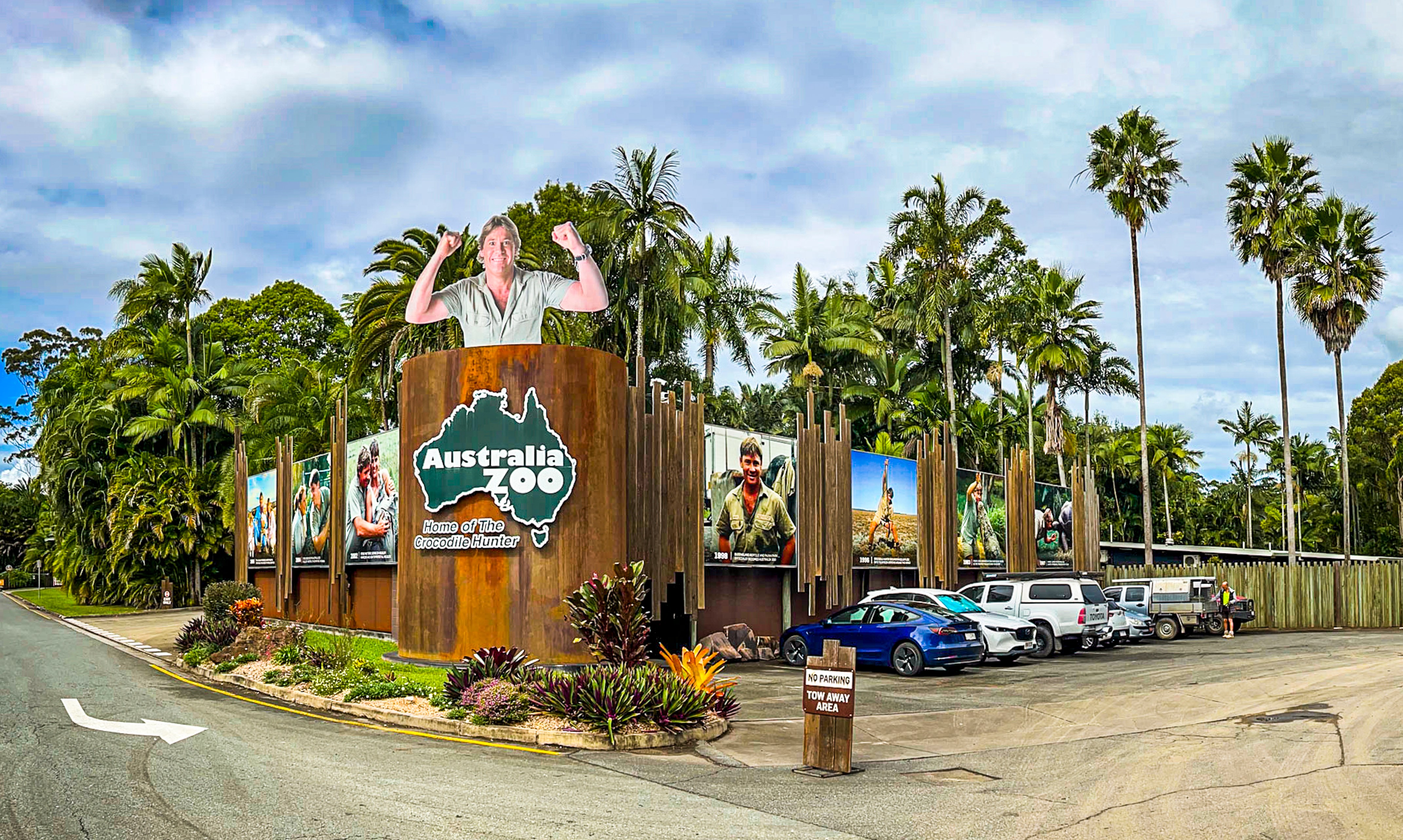 The entrance to Australia Zoo with a large cutout of Steve Irwin and a parking lot.