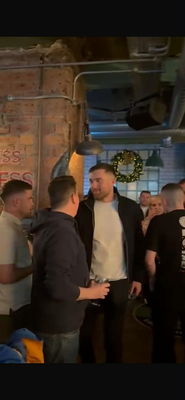 John Souttar stands with punters inside the pub. 