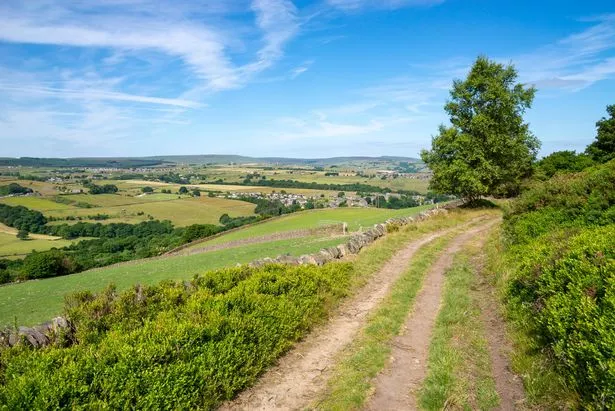 View from Cheese Gate Nab Side across green fields around the village of Hepworth with the Pennines in the background.