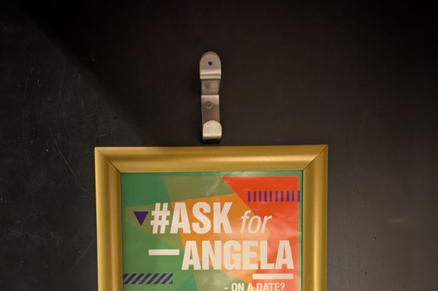 A poster explaining how to ask for Angela on the back of a toilet door in All Bar One