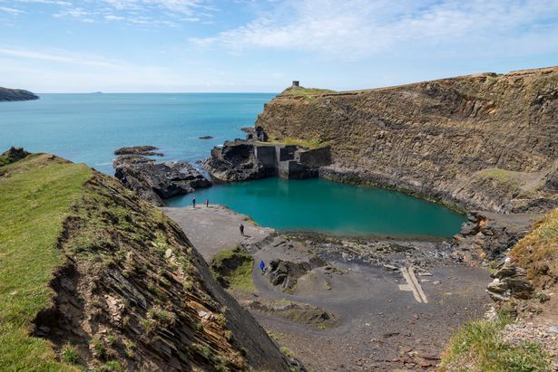 Well known feature in the Pembrokeshire coast national park. An old quarry flooded by the sea to create a deep blue pool. Remains of the old buildings by the water.