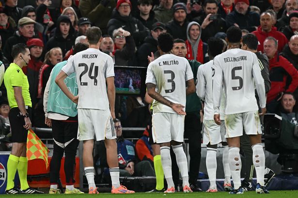 Real Madrid players surround Istvan Kovacs as he consults the pitch-side monitor at Anfield.