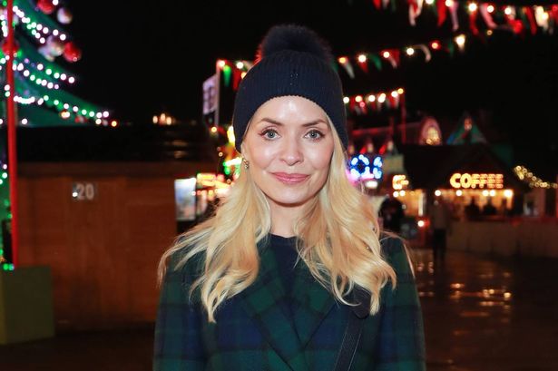 Holly Willoughby wearing green and blue check coat, navy blue bag and navy blue beanie hat