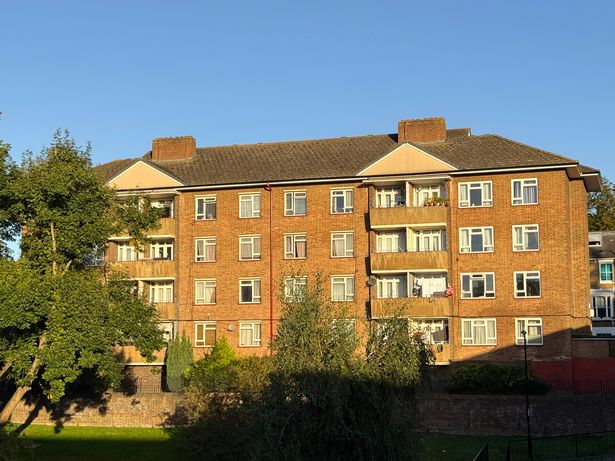 Stock photo shows a modern apartment blocks with red brick built flats in a London suburb, exemplifying council-style housing. This suburban residential scene highlights urban architecture, community living, and affordable housing solutions