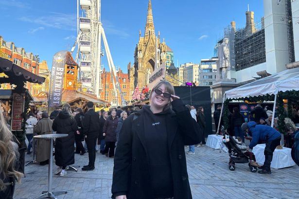 Vita Molyneux smiling in front of a Ferris Wheel at a Christmas Market