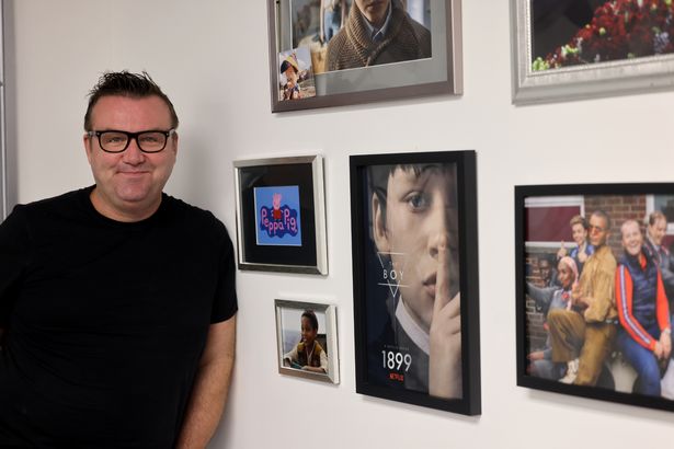 Mark standing with portraits of some of the children he's trained 