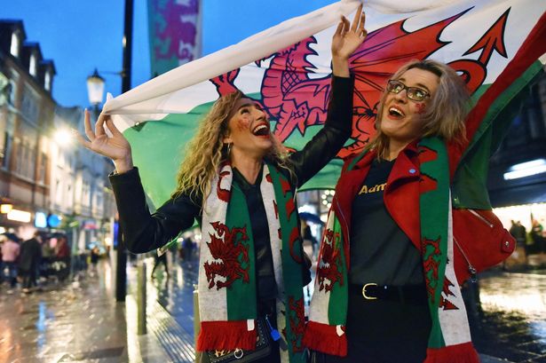 Two Cardiff fans singing in the rain on St Mary Street