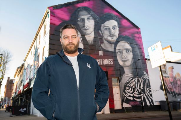 Daniel Davies on Victoria Road in New Brighton, by a mural of the local rock band The Mysterines