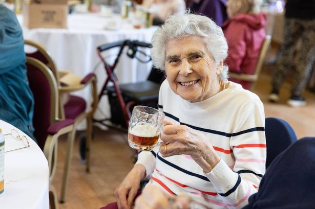 An old person holding a glass of beer