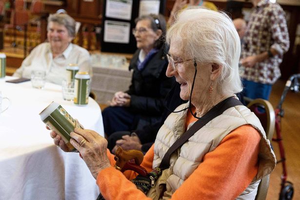 An old woman looking at a can of beer