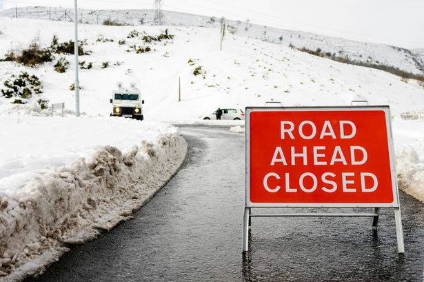 Police close a road because of very heavy snow drifts after a blizzard