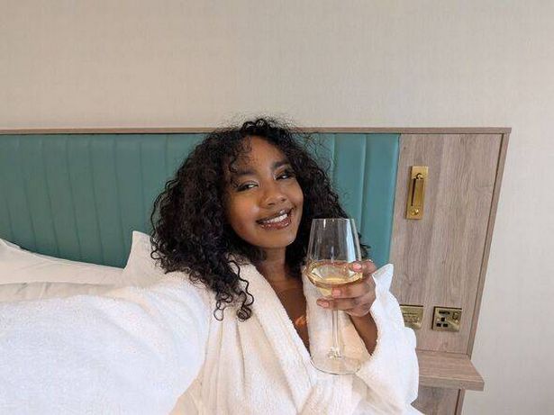 Shania with a glass of wine in a robe