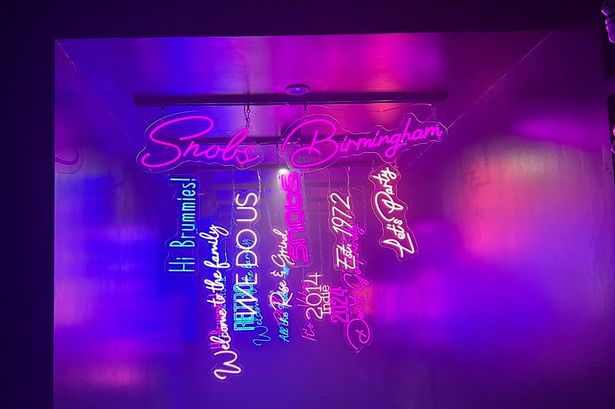 A neon sign in Snobs with Birmingham related words hanging down 