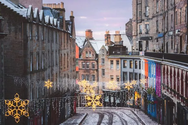 Christmas decorations and the colourful shopfronts of Victoria Street in Edinburgh's old town on a winter morning after a fresh overnight snowfall.