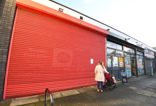 A young mum reads the notice on closed Woolton Post Office.