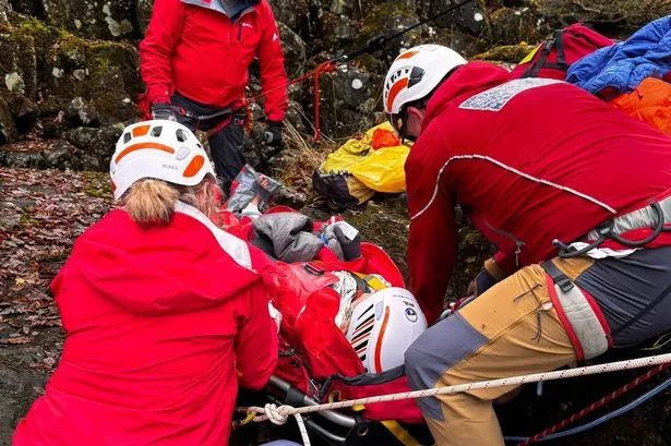 People wearing helmets around a woman on a stretcher 