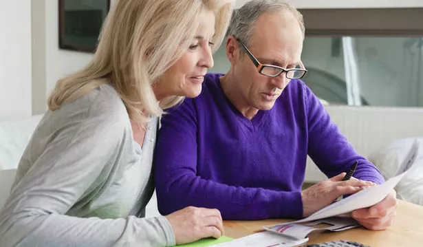 An older man and woman are sitting at a table looking over paperwork 