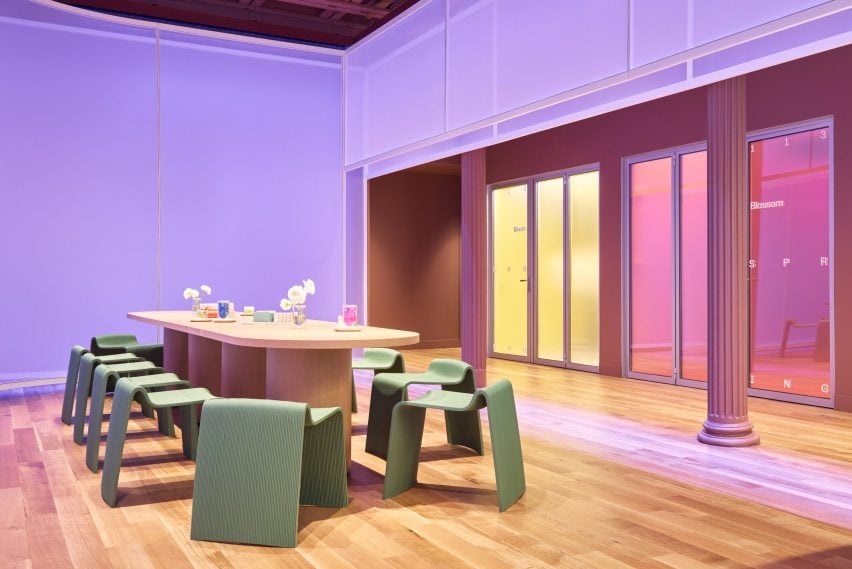 Purple-lit space with a wooden table surrounded by pale green chairs