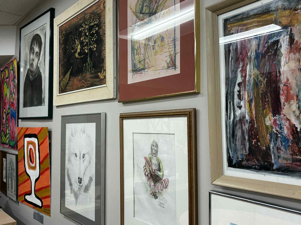 Artwork framed and put on a wall. Some images include a wolf pencil drawing and an abstract painting