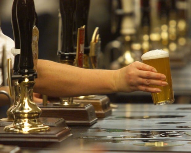Bartender handing a beer to a customer across a bar