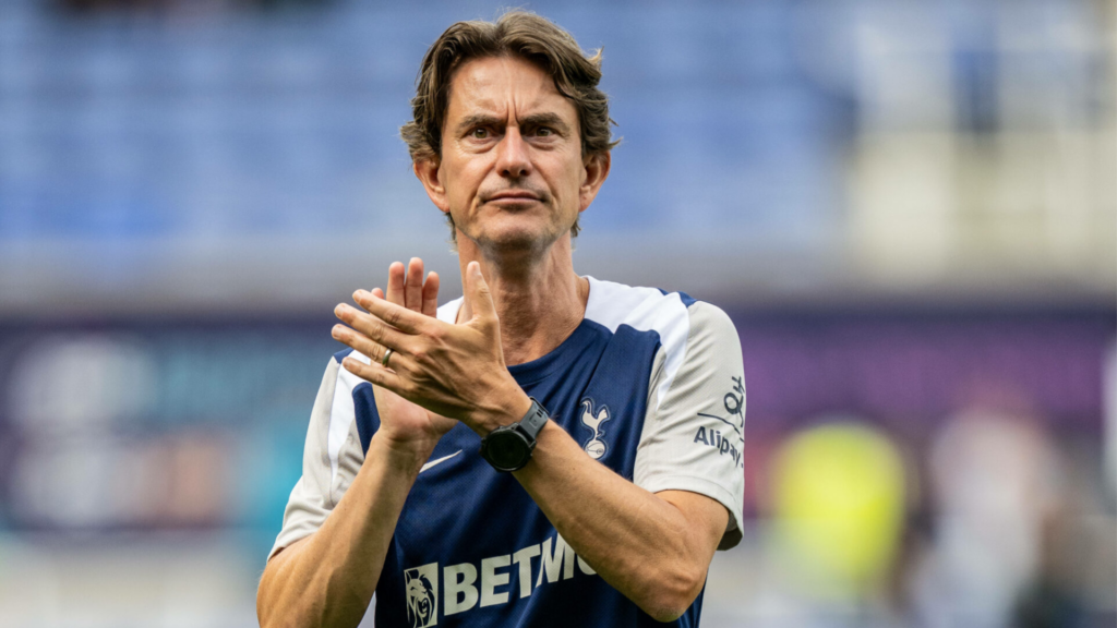 Tottenham manager Thomas Frank applauds after a game with a stern expression on his face.