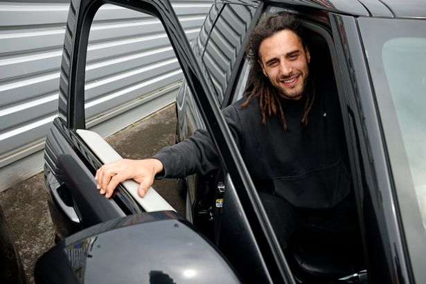 Josh Navidi posing in a car