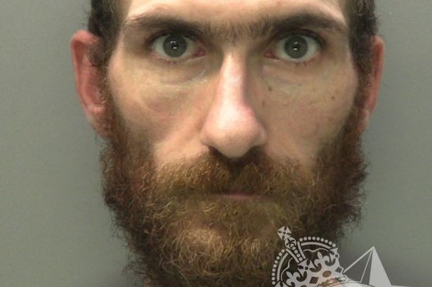 Custody photo of Craig Dowding, 34, who has short black hair, a black beard and is wearing a grey tracksuit.