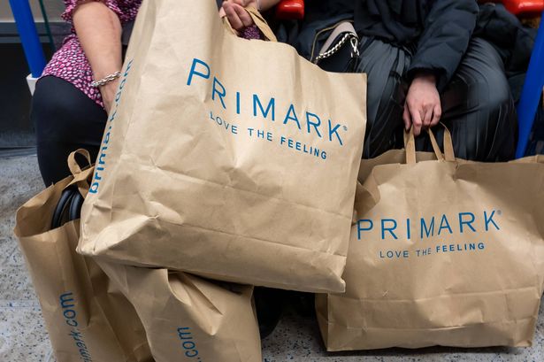 Two shoppers holding several Primark bags