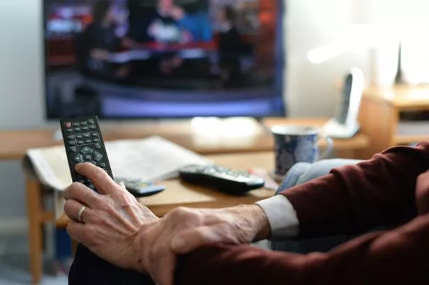 A man watching TV, with a remote control in his hand