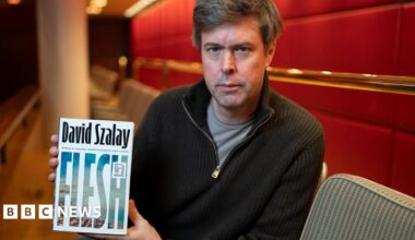 David Szalay holding up the cover of his novel Flesh