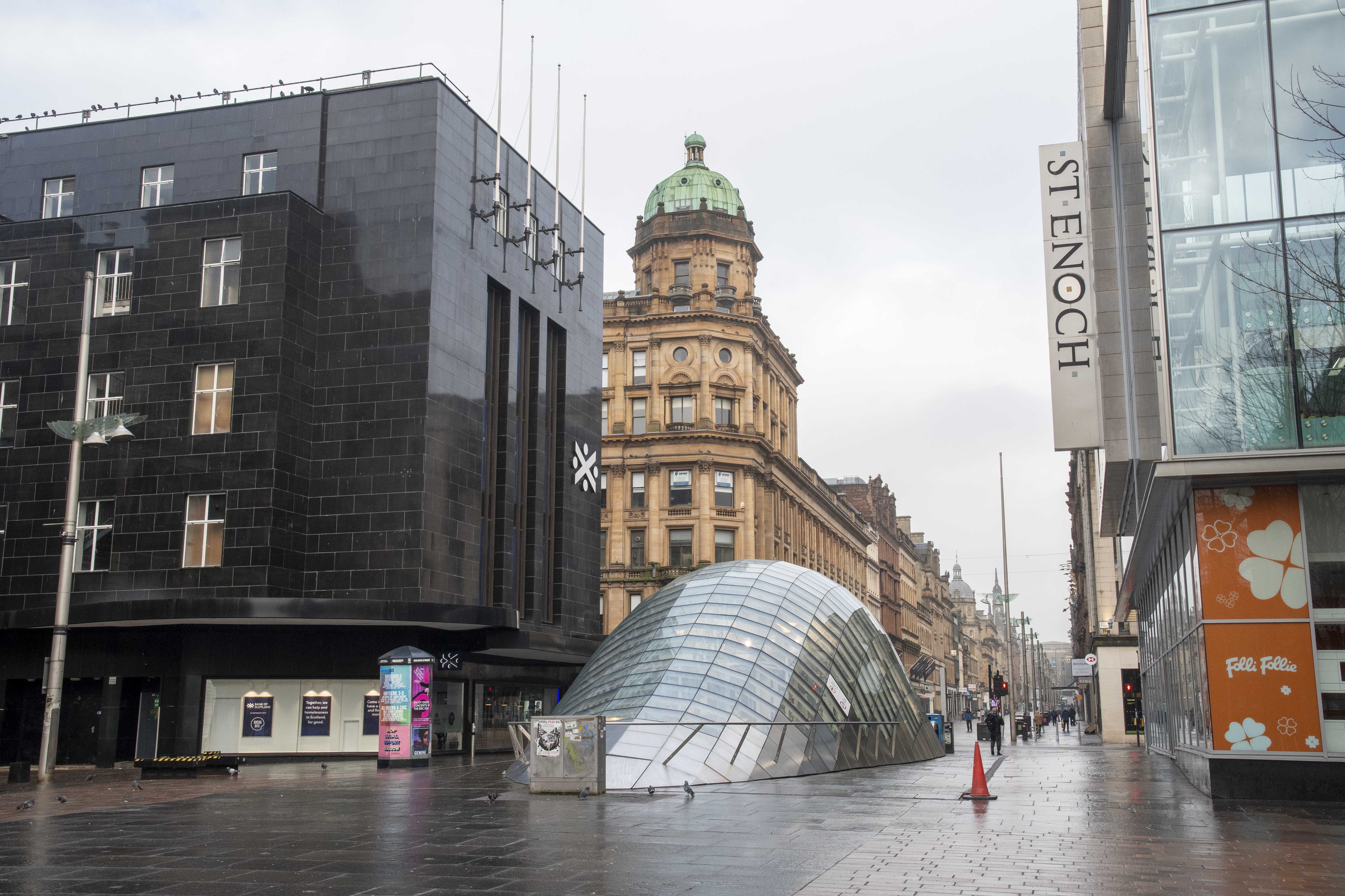 St Enoch Square in Glasgow city center, deserted on a rainy day, with modern and historic buildings visible.