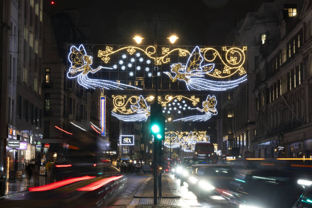 cars passing underneath a glimmering christmas lights display featuring winged fairies in flight