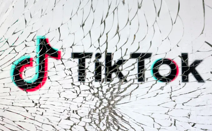 The TikTok logo is seen through broken glass in this illustration.