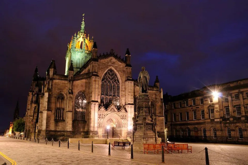 The cathedral is light up against a dark sky.