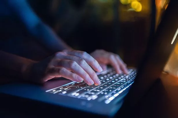 Close up of woman's hand typing on computer keyboard in the dark, working late on laptop at home