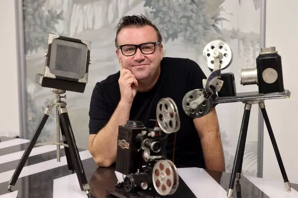 Mark Jermin posing with mock cameras, looking at the camera