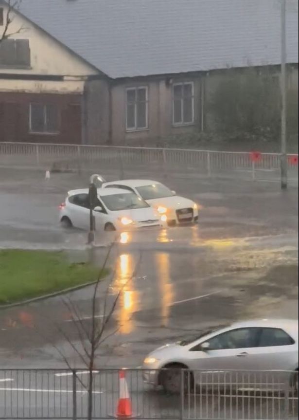 Cars try to navigate the roundabout in flood water on Tuesday afternoon