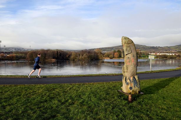 A man running on a path at the top pond of the Waterworks Park in North Belfast