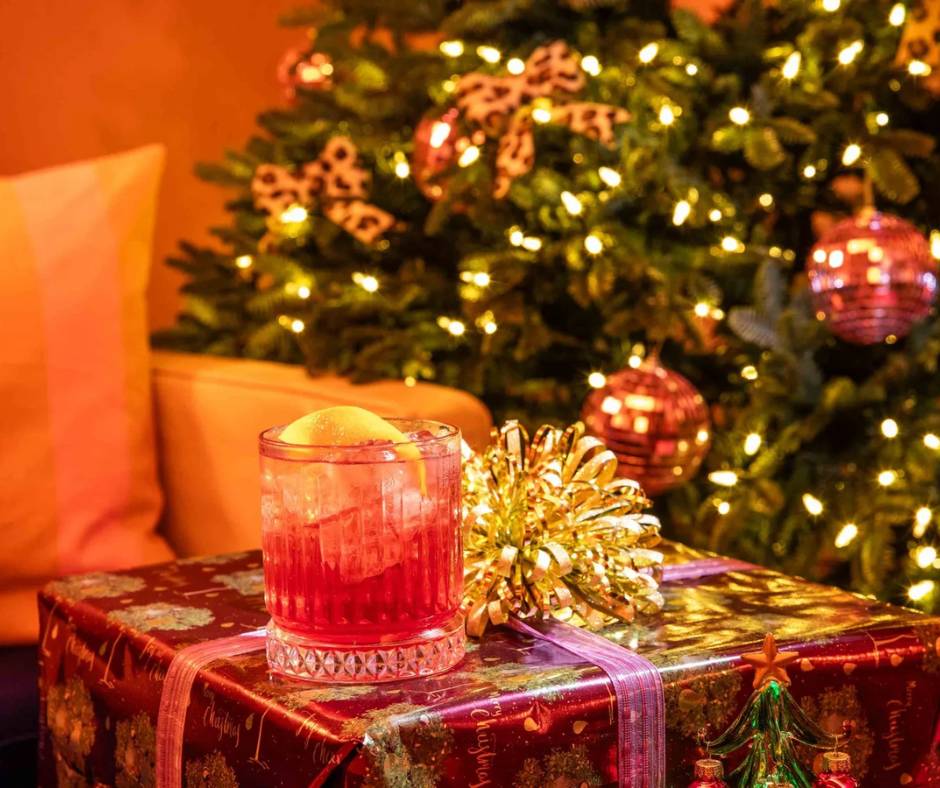 christmas cocktail on top of a present in front of a christmas tree