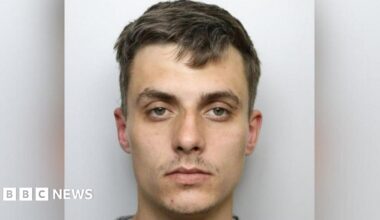 Custody shot of Regan Kemp. He has short brown hair, has a serious expression and is stood in front of a grey background.