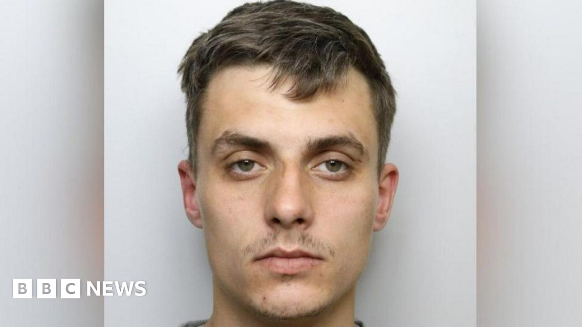 Custody shot of Regan Kemp. He has short brown hair, has a serious expression and is stood in front of a grey background.