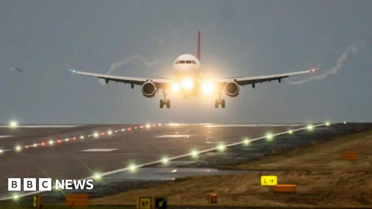 An aeroplane takes off from a runway against the backdrop of a gloomy sky.