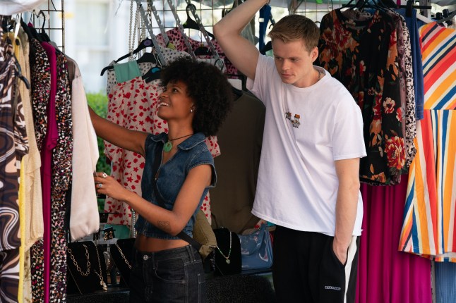 Oscar stands behind Jasmine as she peruses a market stall in EastEnders
