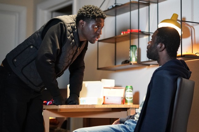 Okie looms over Kojo in a threatening manner in EastEnders