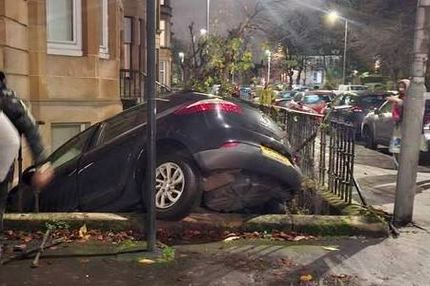 The car has crashed into railings surrounding a tenement building 