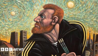 Peter Howson, a man in his 60s with short, grey hair is wearing a dark green sweatshirt. He is standing next to Ross Muir, who is in his 40s and has shoulder-length, brown curly hair, and a beard and moustache. He is wearing a yellow beanie hat, a yellow hoodie with splashes of paint on it, and blue denim overalls.