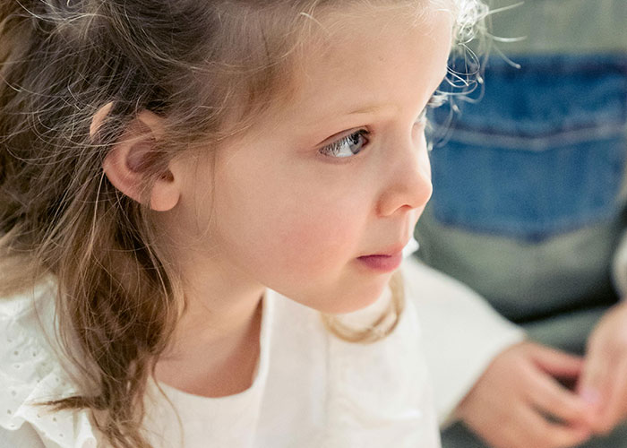 Young girl in a white shirt looking to the side, capturing a moment related to psychiatric institution workers' unforgettable experiences.