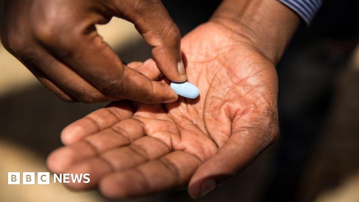 Close-up of a man's hands with a large, oval-shaped light blue pill in one of his palms.