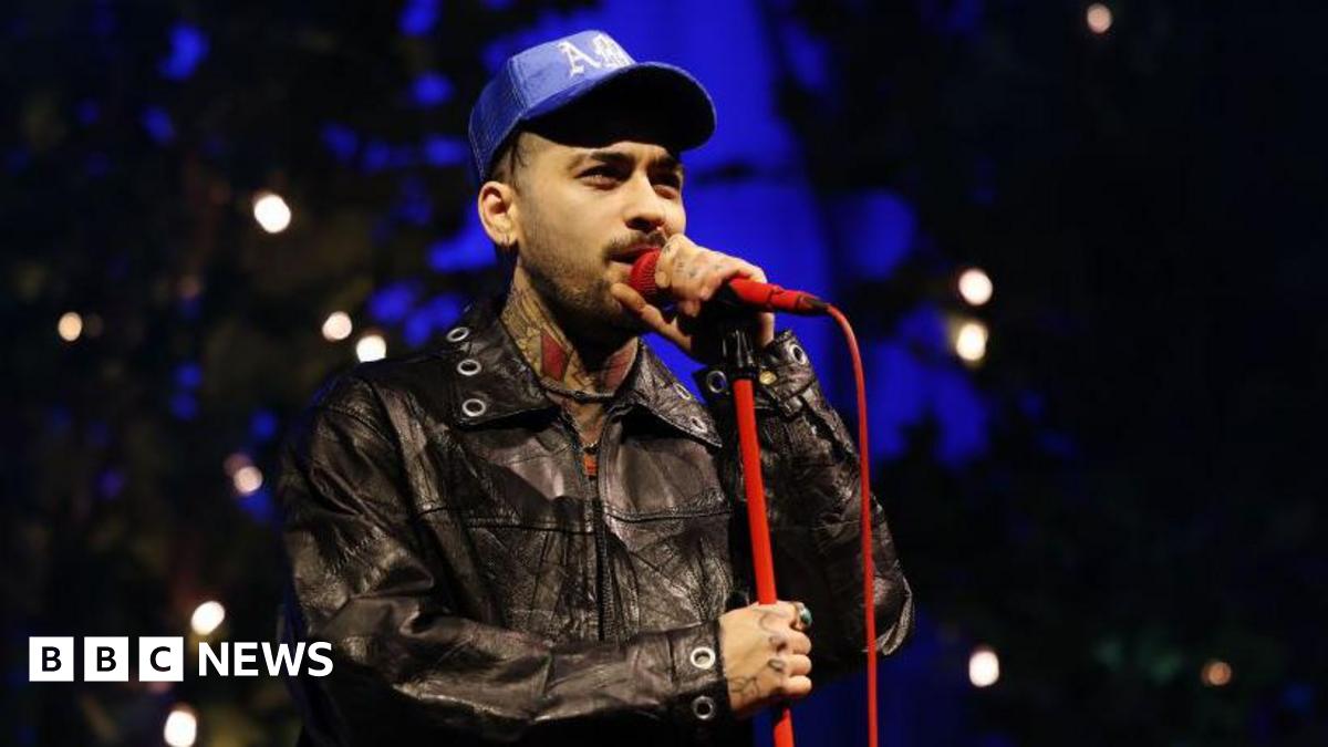 Zayn Malik singing into a red microphone while performing at O2 Academy Leeds